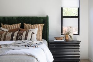 black nightstand, velvet green headboard, masterbedroom, white duvet, patterned throw pillow